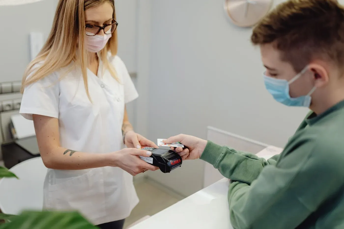 A patient paying by card at a dental clinic reception desk