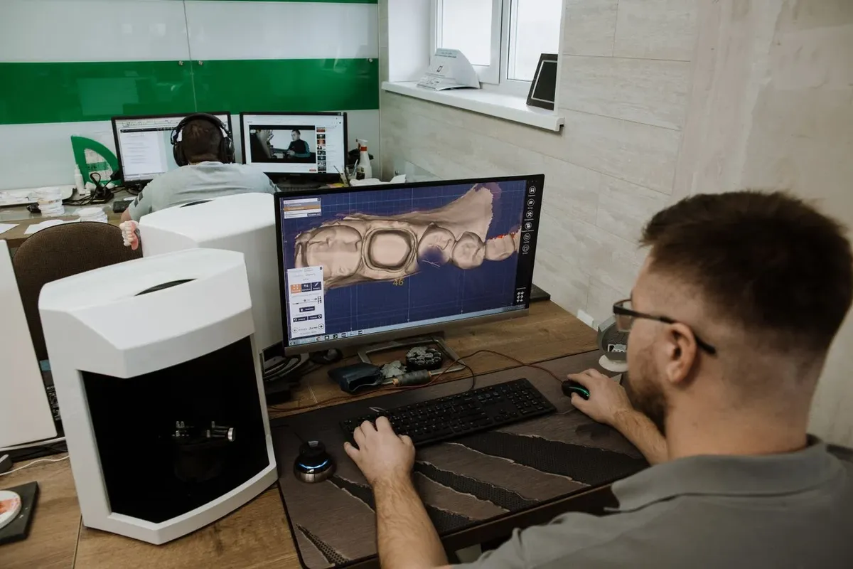 A technician creating a 3D digital model of teeth on a computer in a dental laboratory