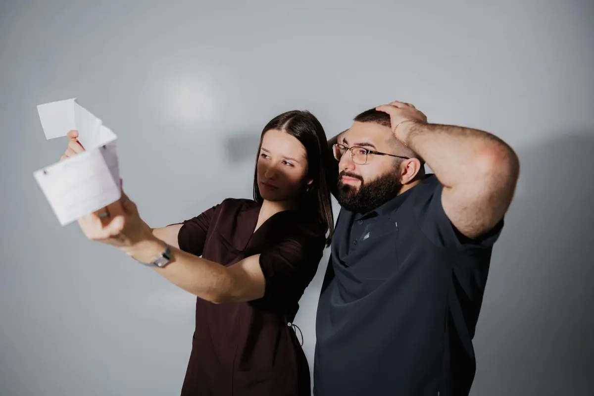 A man and woman looking surprised while examining a printed statement together