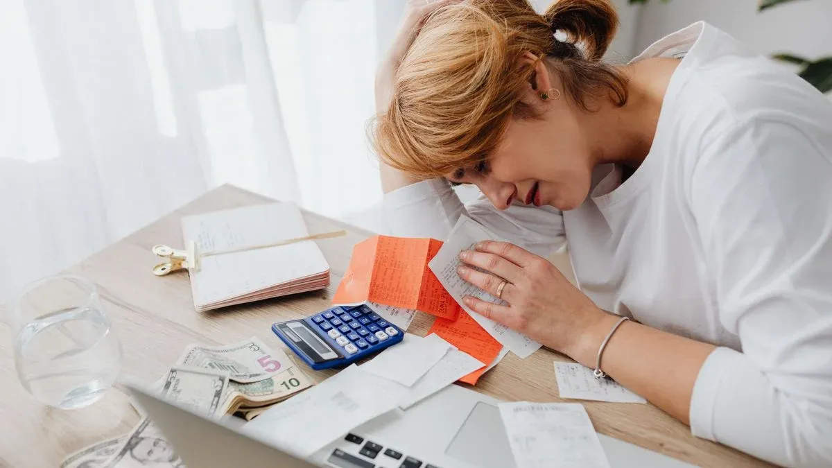 Woman at home surrounded by bills, a calculator and cash while facing rising healthcare costs