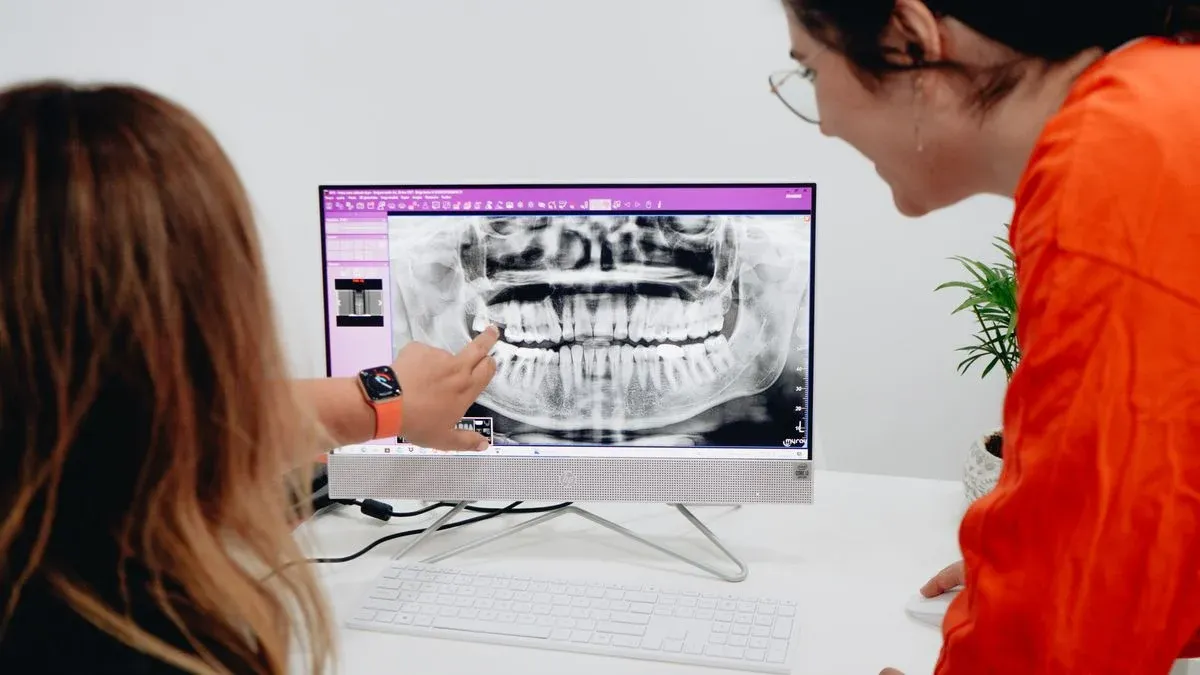 Two women reviewing a panoramic dental X-ray on a computer screen in a dental clinic