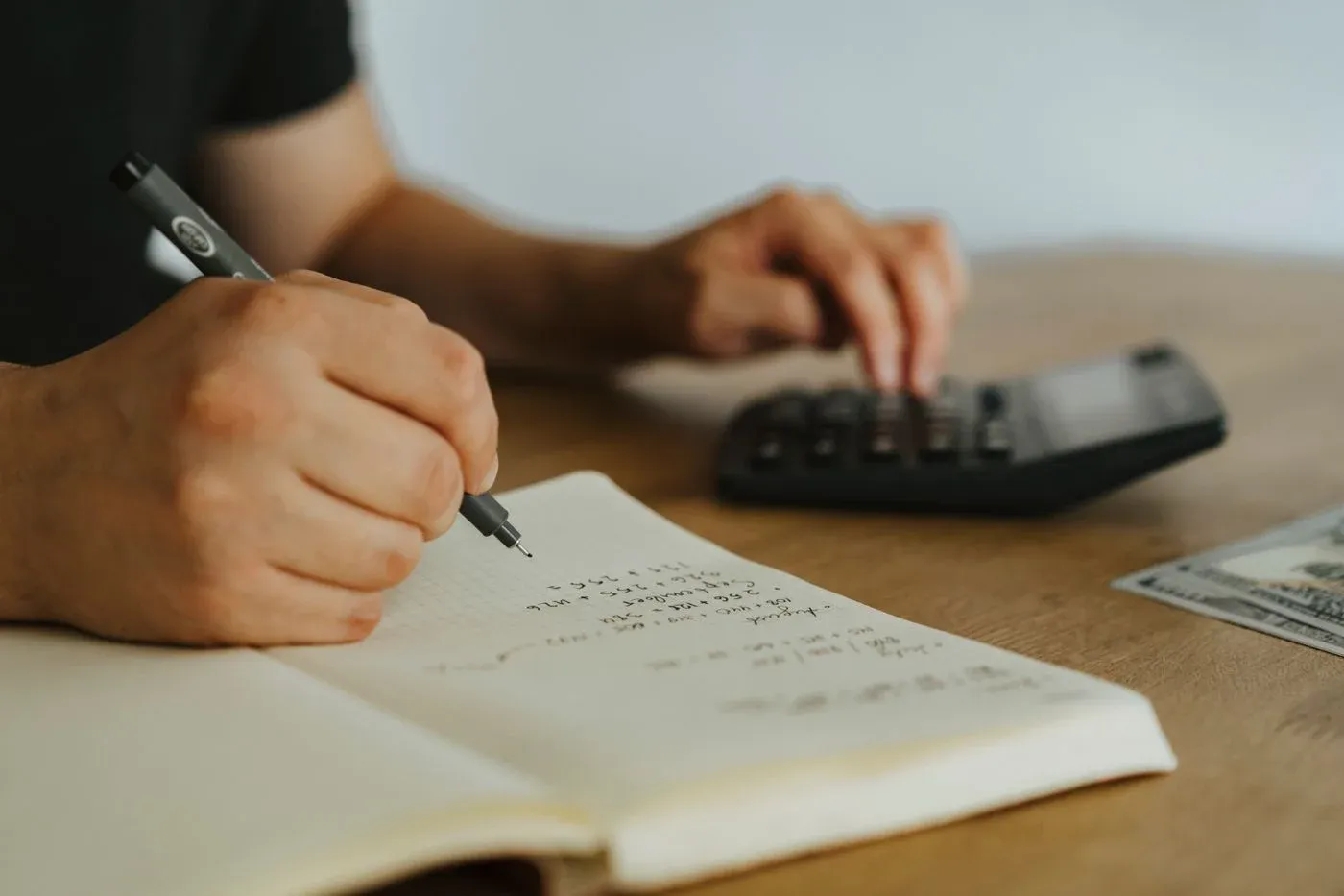Self-employed worker using a calculator and notebook to work out whether dental insurance is worth the premium