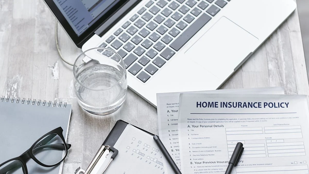 An insurance policy document next to a laptop, used to compare individual dental insurance plans