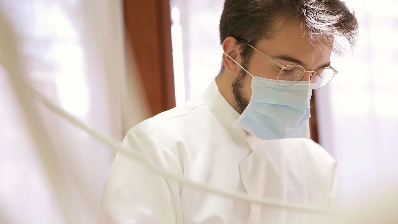 Dentist in white coat and blue mask at a dental office — individual dental insurance plans from Aetna and Delta Dental both cover restorative procedures at 80% for basic and 50% for major work