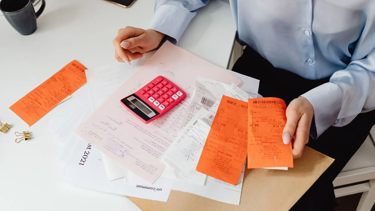 A person reviews receipts and uses a calculator to calculate dental crown out-of-pocket costs after insurance
