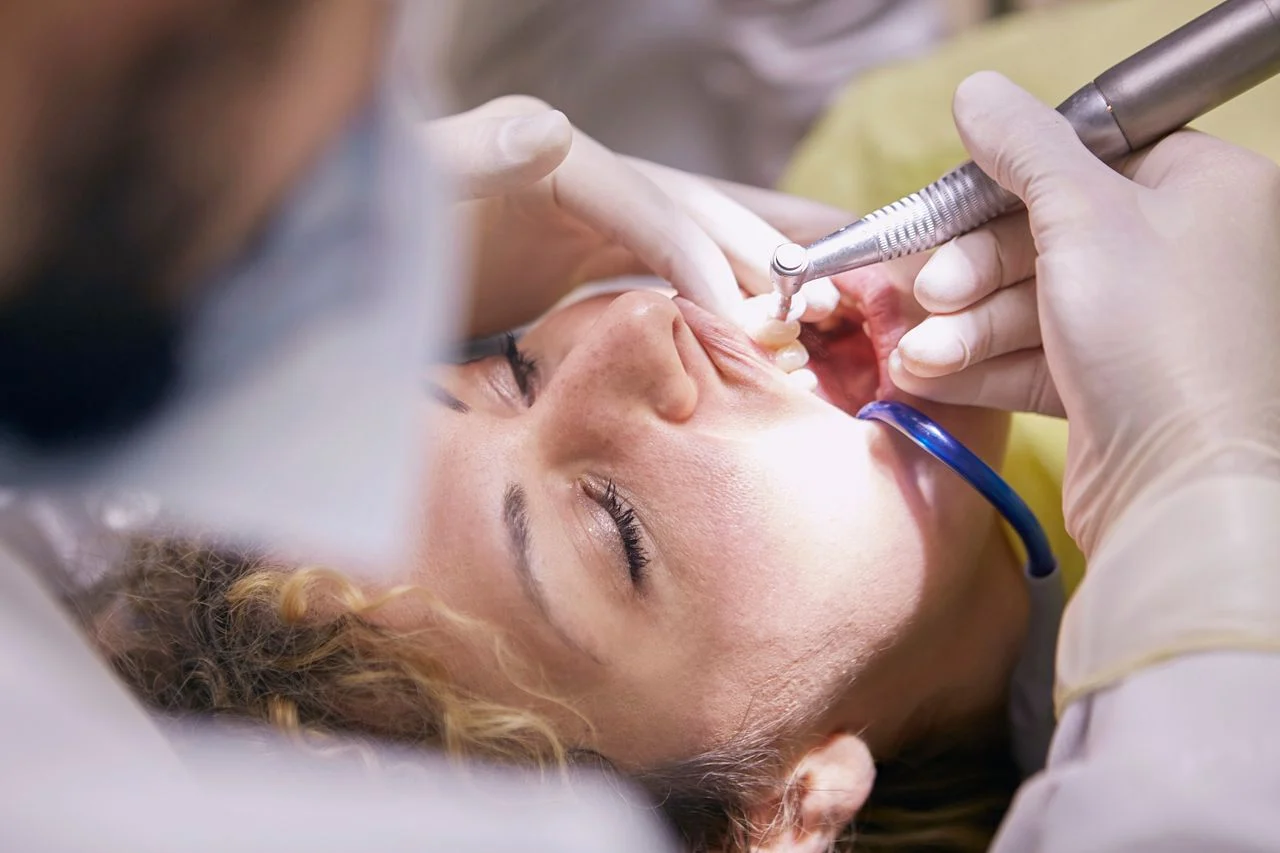 Dentist examining patient during emergency dental visit without employer insurance coverage