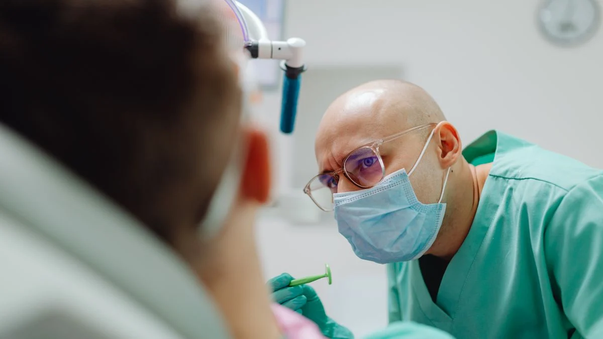 Dentist in a mask examining and consulting with a patient about treatment