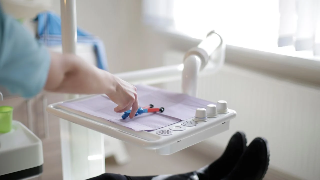 A dental professional in blue gloves selects instruments in a modern dental clinic, preparing for a crown restoration procedure