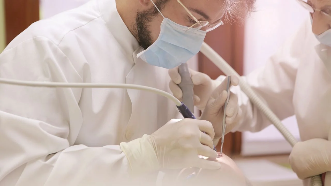 Dentist with mask and gloves performing a dental procedure — major restorative work like root canals and crowns is typically covered at 50% under family dental insurance after the deductible