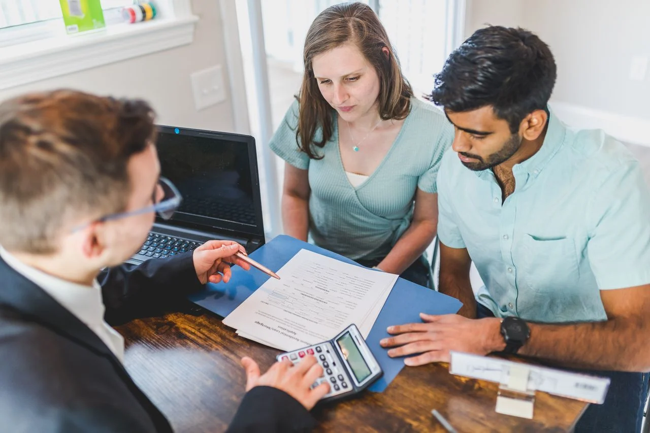 Real estate agent discussing dental insurance coverage options with clients in a professional office setting