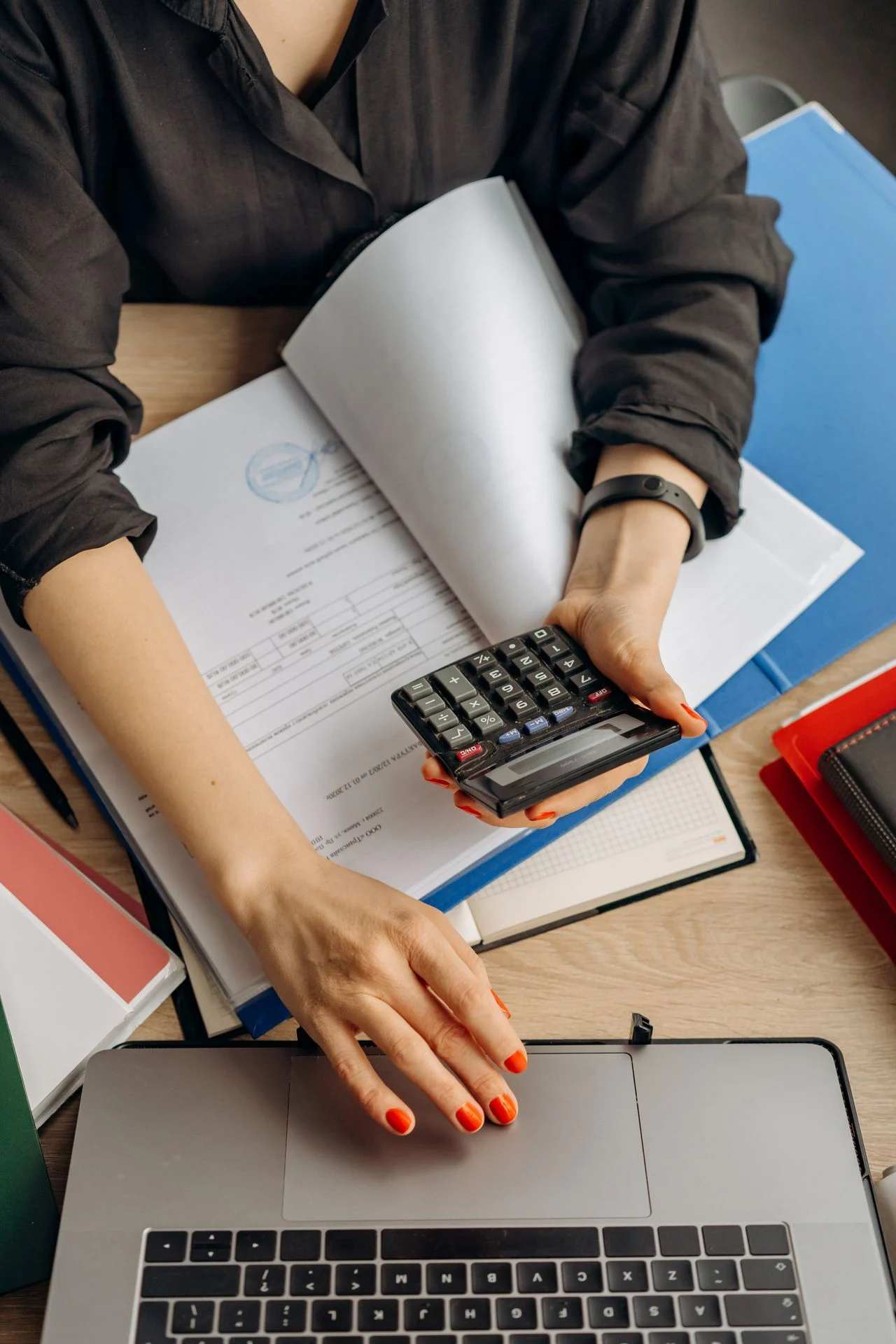 Self-employed worker using a calculator and laptop to compare dental insurance plan costs and association membership fees