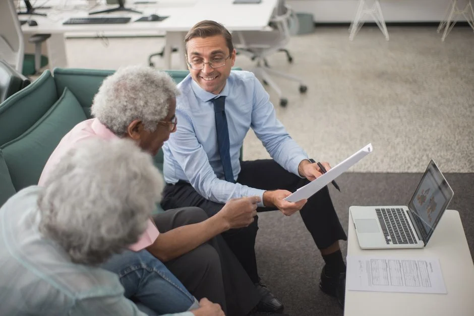 Senior couple reviewing dental coverage options with an advisor at a laptop