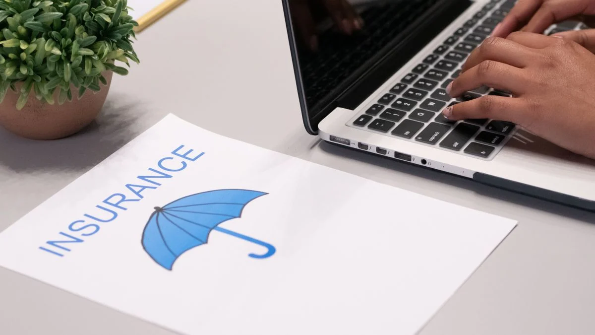 Close-up of hands typing on a laptop with an insurance document on the desk, representing comparing marketplace and standalone dental coverage