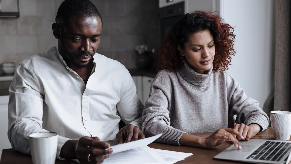 Couple reviewing documents together on a laptop at home while weighing dental coverage options