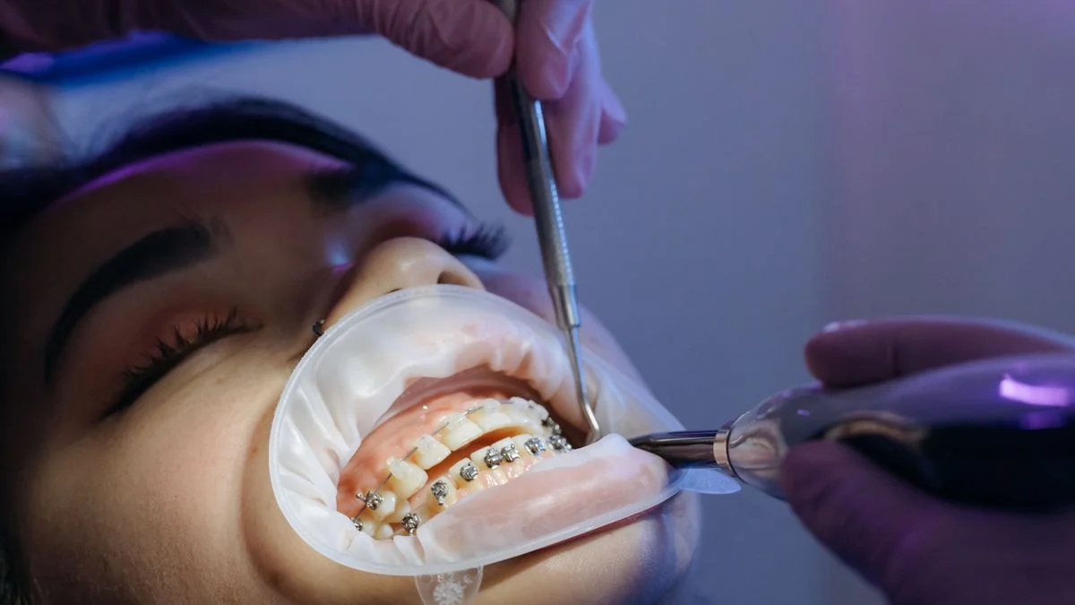Dentist performing an orthodontic procedure on a patient wearing braces in a clinic setting, illustrating the child orthodontic benefit on Ameritas PrimeStar Boost
