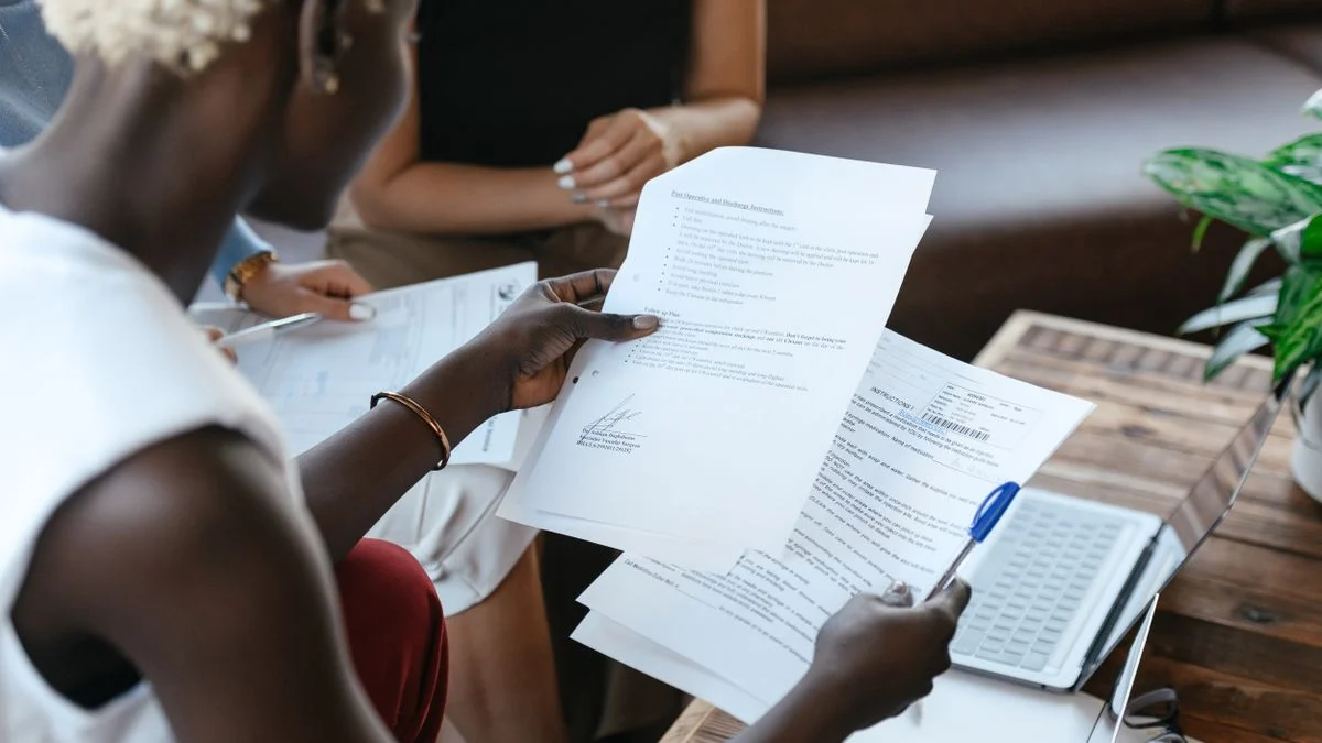 Person comparing figures across two printed documents at a table while weighing competing dental plans