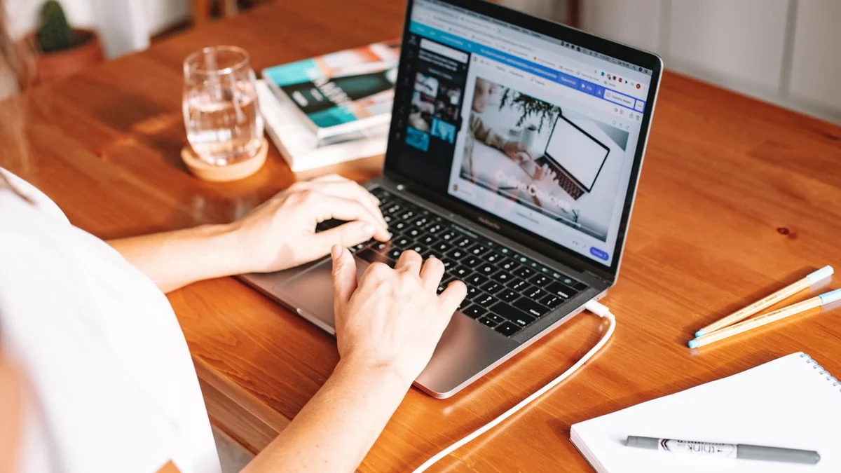 Person working at a wooden desk with a laptop and notepad while researching and shortlisting dental plans