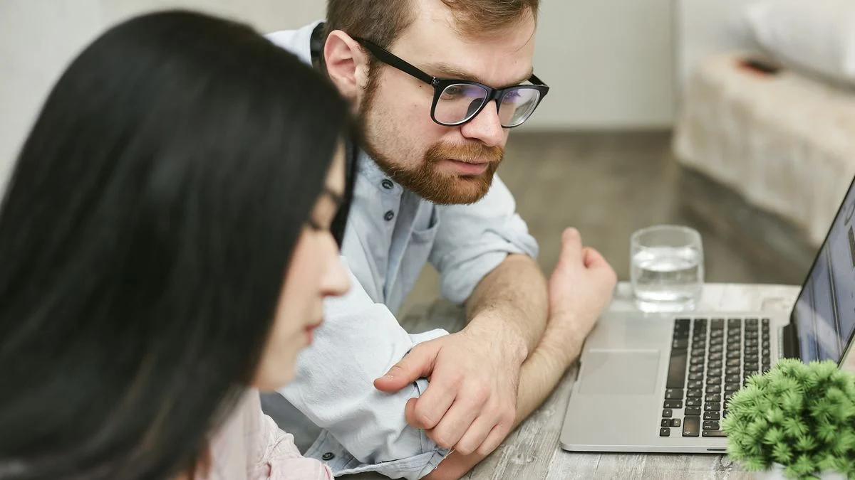 A man and woman sitting at a table comparing dental insurance quotes on a laptop