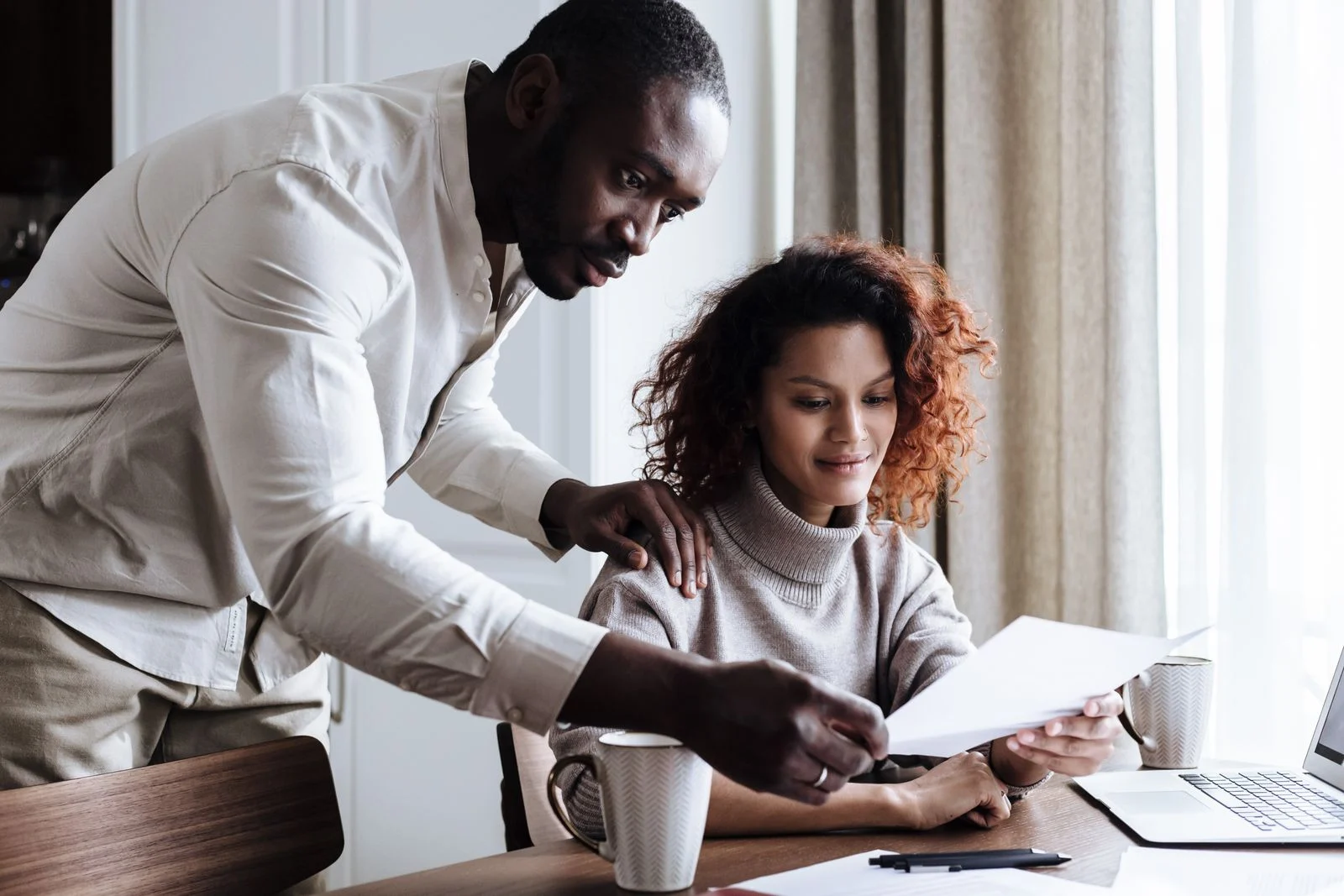 A couple reviewing insurance documents together at home with a laptop