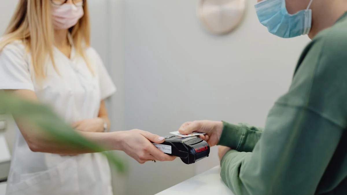 Patient paying by credit card at a medical reception desk, representing the share of the bill that coverage does not absorb