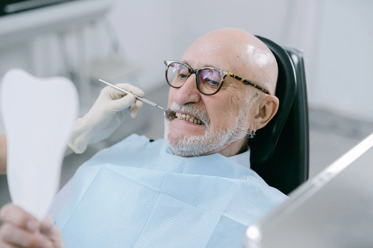 Smiling senior man in a dental chair during a checkup after enrolling in coverage