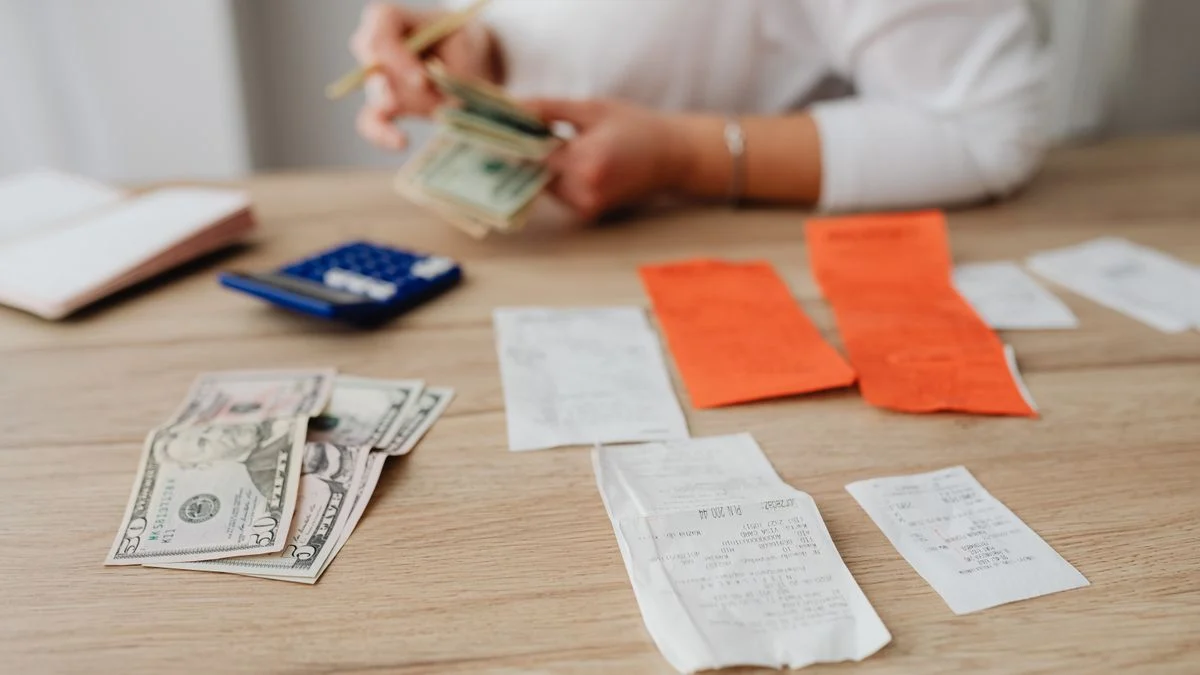 Person using a calculator and cash to work through what a dental deductible will cost before coverage starts