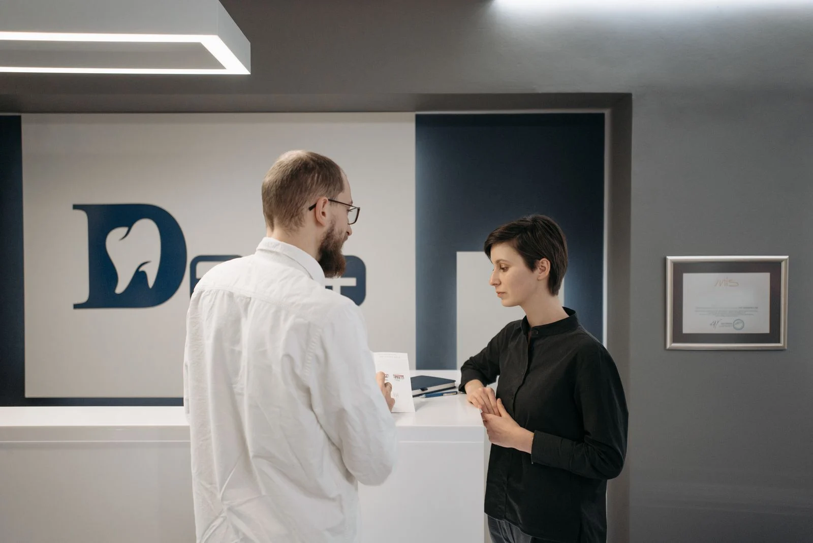 Dentist consulting a patient at a modern dental clinic Dentist consulting a patient at a modern dental clinic reception desk