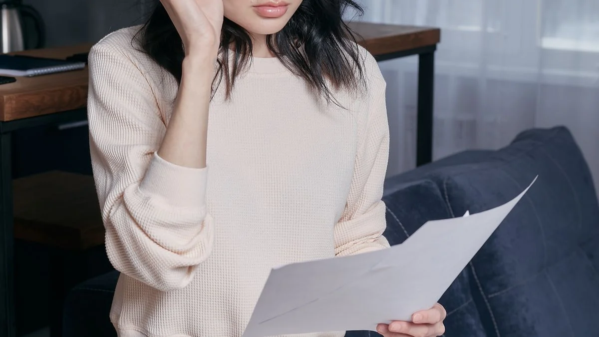 Woman with eyeglasses reviewing financial paperwork at home