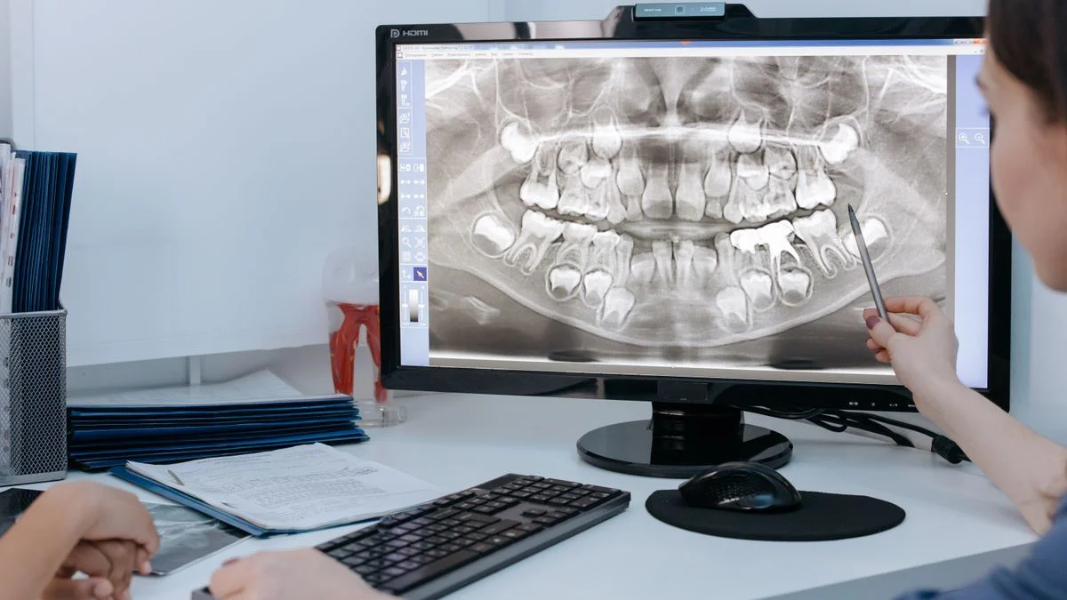 Dentist reviewing a patient's dental implant x-ray on a computer screen in a clinic.