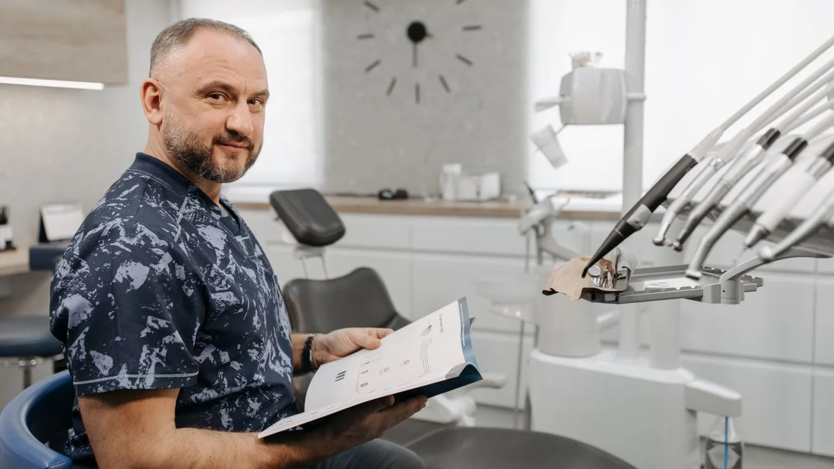 A dentist reviews a patient's dental insurance paperwork and records in a modern clinic setting.