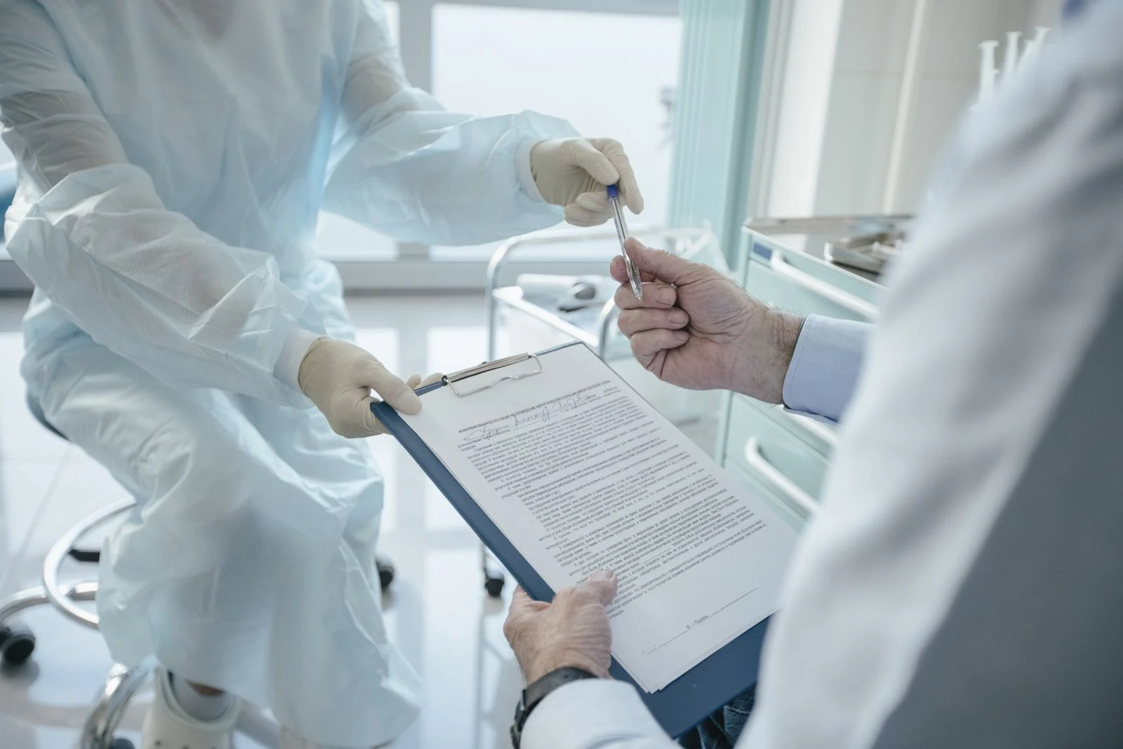 Patient signing insurance paperwork with healthcare provider A patient signing paperwork while reviewing insurance documents with a healthcare provider