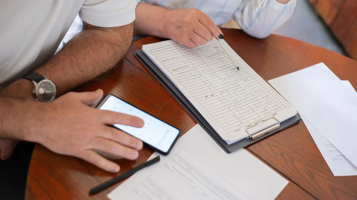 Senior couple at home reviewing bills and paperwork with a clipboard and smartphone while comparing dental plan costs