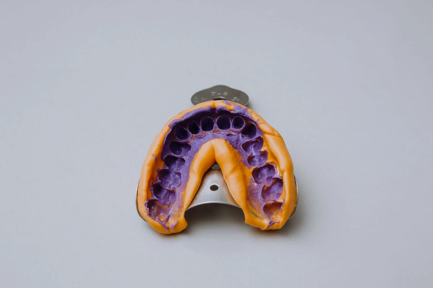 Dental impression tray with alginate putty used for a home night guard mold, top view on a white background