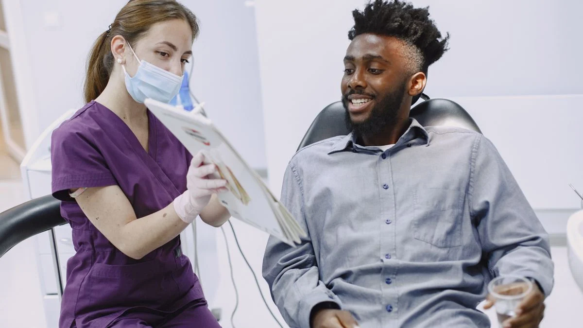 Dentist explaining treatment and coverage options to a patient during a checkup, illustrating how PPO and HMO plans differ in provider choice