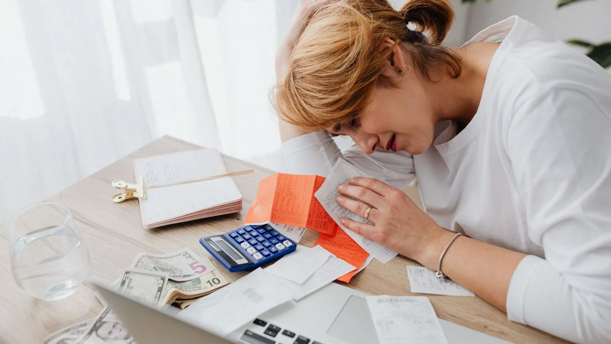 Woman at home surrounded by bills, a calculator and cash while facing rising healthcare costs
