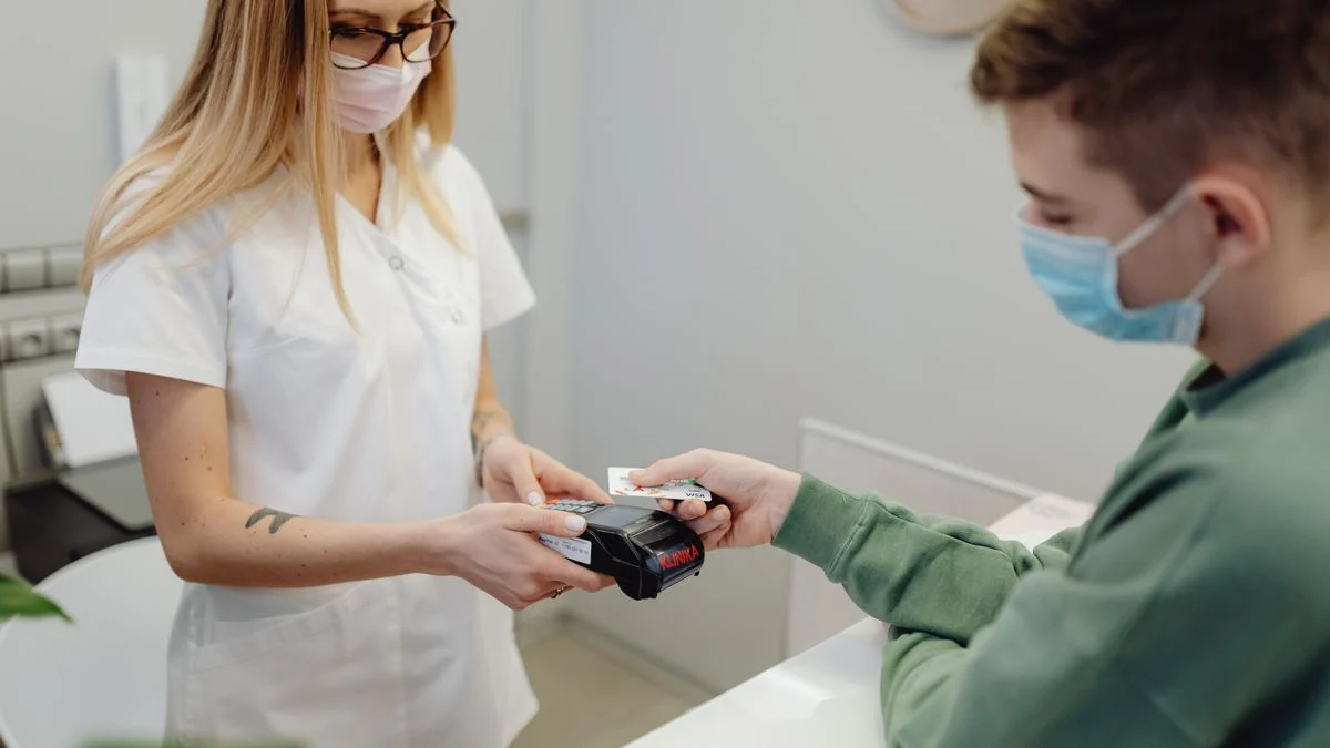 Healthcare professional processing a patient card payment at a dental clinic reception desk