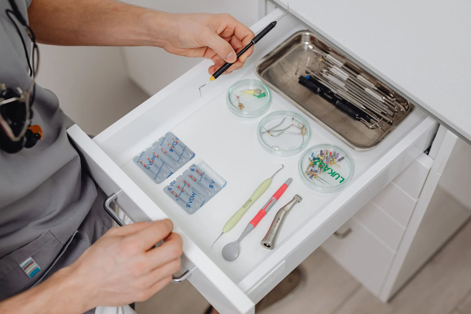 Dentist arranging tools and equipment in a clinic drawer Dentist arranging dental tools and equipment in a clinic drawer