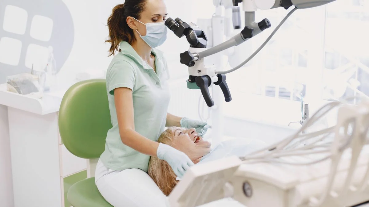 Dentist using a dental microscope during a root canal treatment Dentist using a dental operating microscope while treating a patient, the precision equipment commonly used for root canal procedures