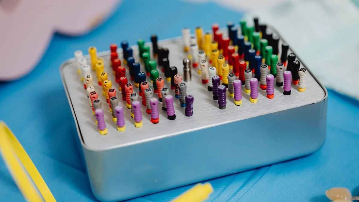 Close-up of colorful dental endodontic files arranged in a sterilization tray, the instruments used to perform a root canal