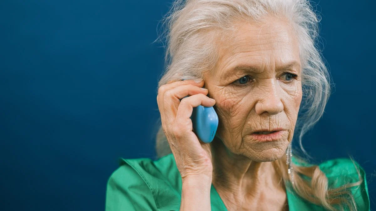 Senior woman on the phone checking a Medicare Advantage dental directory A senior woman with gray hair talks on her mobile phone against a blue background, checking a plan directory.