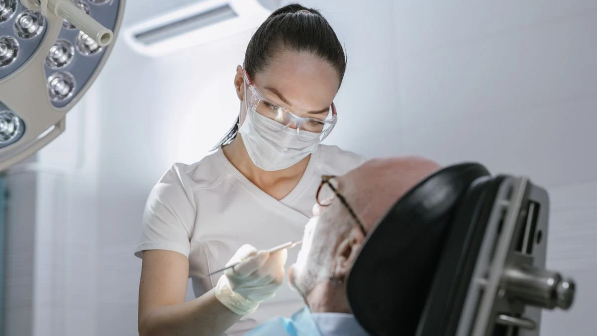 Dental professional attending to an elderly patient in a clinic, representing the major restorative work seniors most often need