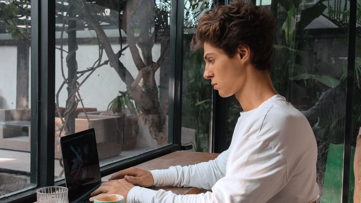 Self-employed freelancer working from a cafe, considering UnitedHealthcare dental insurance Freelancer typing on a laptop in a cafe, the kind of self-employed worker who buys individual UnitedHealthcare dental insurance without an employer plan