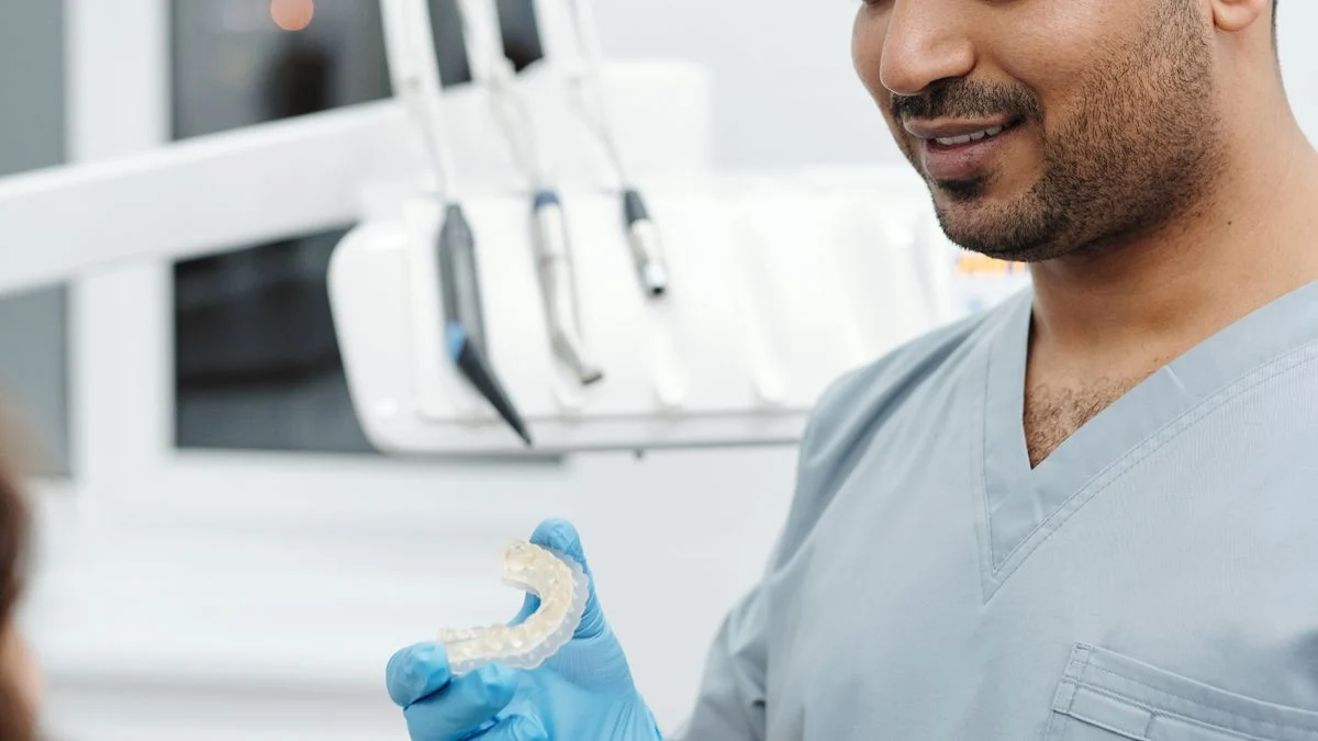 A dentist showing a clear dental aligner to a patient during a treatment consultation