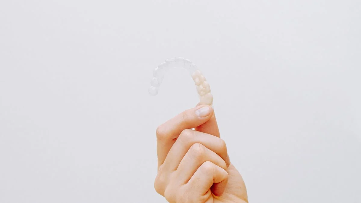 Hand holding a clear Invisalign aligner Close-up of a hand holding a clear dental aligner, illustrating Invisalign clear aligner treatment