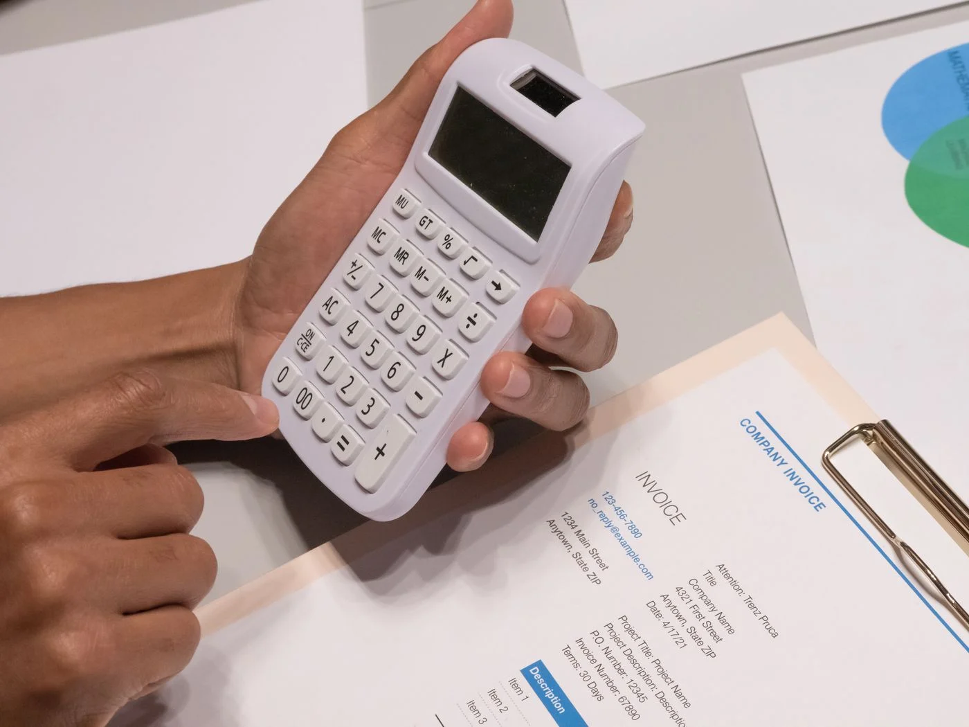 Close-up of hands using a calculator next to an itemized invoice