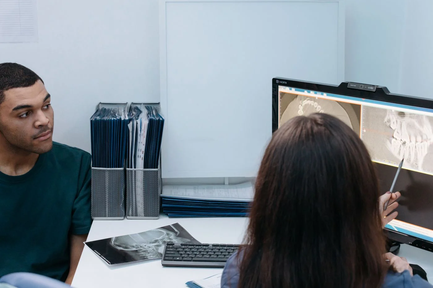 A dentist and patient reviewing a dental X-ray on a screen in a clinic